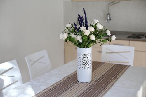 a white vase with white flowers on a table at Apartments Andreja in Pag