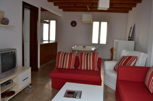sala de estar con sofá rojo y TV en Casa Fayas, en Ciutadella