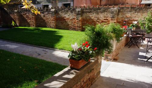 a garden with a brick wall with flowers in a pot at B&B HORTUS in Venice