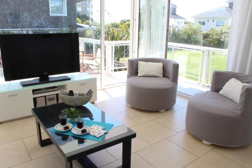 a living room with a tv and two chairs and a table at Apartamento Playas Carilo in Carilo