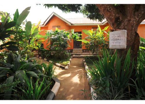 a garden with an orange house and a tree at Gorilla African Guest House in Entebbe