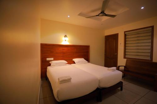 a bedroom with a white bed with a wooden headboard at Roses Inn Fortkochi in Cochin