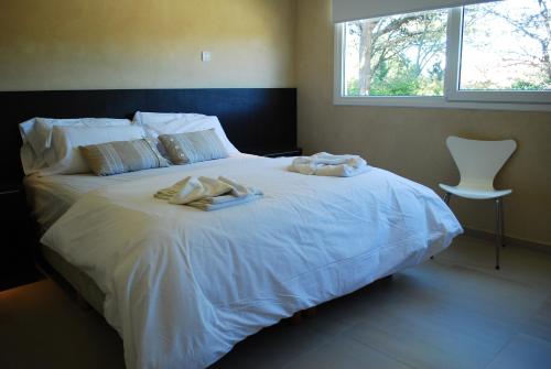 a bedroom with a white bed with towels on it at Silenios in Pinamar