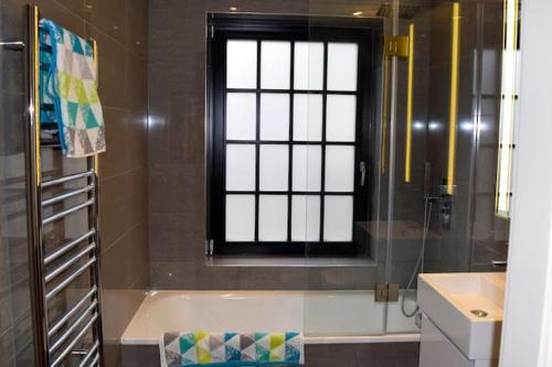 La salle de bains est pourvue d'une baignoire et d'une fenêtre. dans l'établissement Kings Cross Apartment 5/Apartment, à Londres