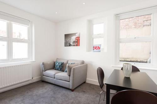 ein Wohnzimmer mit einem Sofa, einem Tisch und Fenstern in der Unterkunft Kennington Apartment 1/Apartment in London