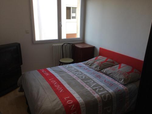 a bedroom with a bed with a red headboard and a window at Appartement Granville in Granville