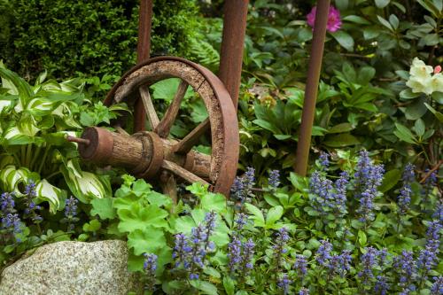 a garden with purple flowers and a water wheel at Hotel Villa Rosa in Allershausen