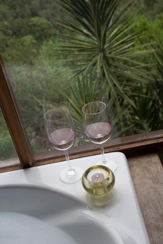 two wine glasses sitting on a table next to a window at Forest Valley Cottages in Knysna