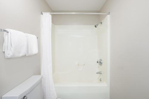 a white bathroom with a shower and a sink at Knights Inn Jacksonville in Jacksonville
