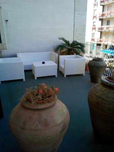 a patio with white couches and tables and plants at Palace B&B in Acquaviva delle Fonti