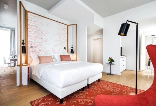 a bedroom with a large white bed and a red rug at Capri by Fraser Berlin in Berlin