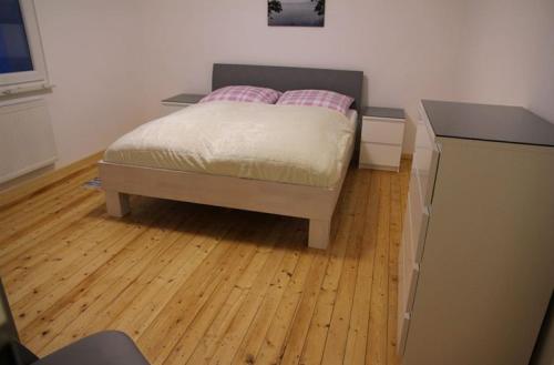 um quarto com uma cama e piso em madeira em Ferienhaus am Kreuzberg - Nürburgring em Ulmen