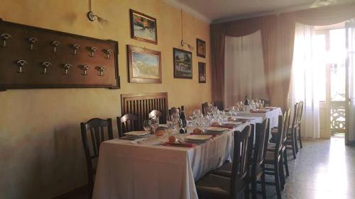 una sala da pranzo con un lungo tavolo con tavoli e sedie bianchi di Affitta Camere Il Commercio a Gabiano