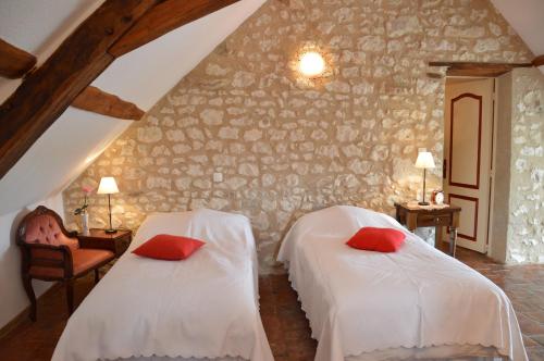 2 łóżka z czerwonymi poduszkami w pokoju w obiekcie Aux Jardin's de la Bosniere w mieście Cussay