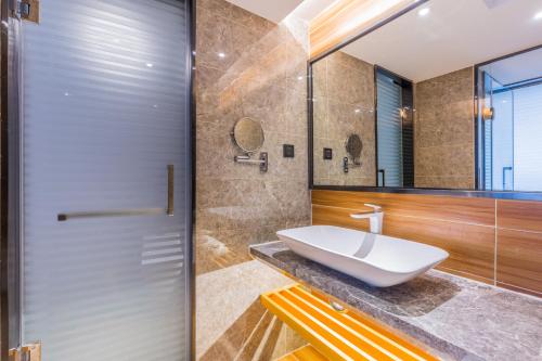 a bathroom with a sink and a glass shower door at Lifu Hotel Wankel Jiang Tai Road Metro Station Branch in Guangzhou