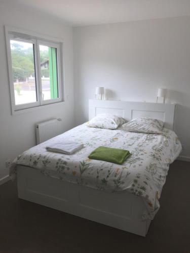 a white bedroom with a bed with a window at Villa Orchidee in Lacanau-Océan