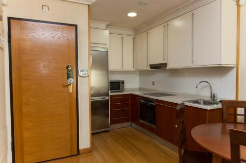 a kitchen with white cabinets and a wooden door at Hotel Sercotel Tres Luces in Vigo