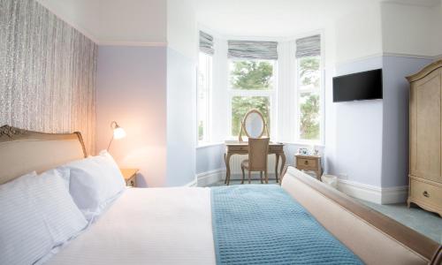 a bedroom with a bed and a desk with a mirror at Gwesty Gadlys Hotel in Cemaes Bay