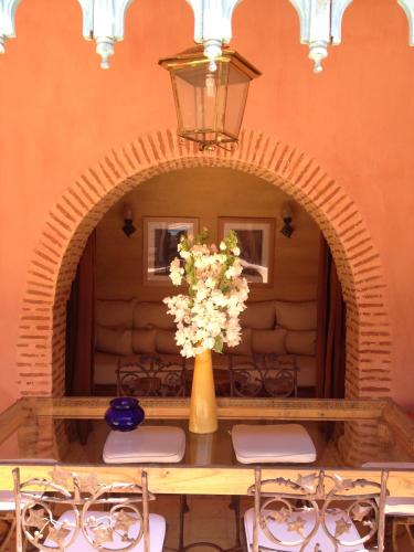 a table with chairs and a vase with flowers on it at Casa Taos in Marrakech