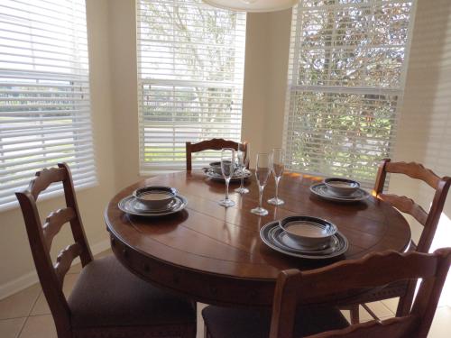 a wooden dining room table with chairs and glasses on it at Formosa Garden Pool Home in Orlando
