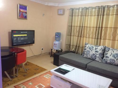 Pumzika Place في نيروبي: غرفة معيشة مع أريكة وتلفزيون بشاشة مسطحة