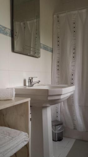 a white bathroom with a sink and a mirror at Vila Olímpica in Albufeira