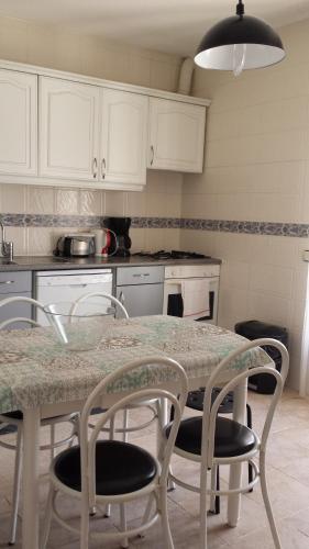 een keuken met een tafel en stoelen en een keuken met witte kasten bij Vila Olímpica in Albufeira