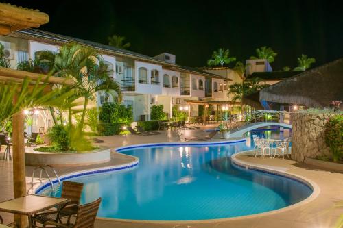 una piscina del complejo por la noche con mesas y sillas en Sarana Praia Hotel, en Porto Seguro