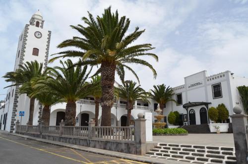 a building with a clock tower and palm trees at Casa Villalba in San Bartolomé