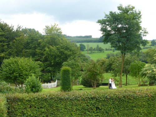a bride and groom walking through a garden at L'orée du bois in Roy