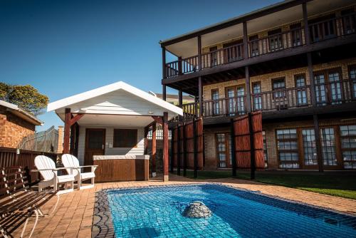 a house with a swimming pool in front of a building at Muzuri Apartment in Jeffreys Bay