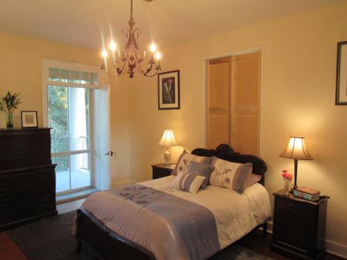 a bedroom with a bed with a chandelier and a window at Concord Quarters in Natchez