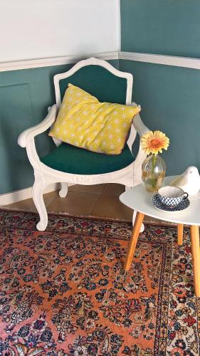 a green chair with a yellow pillow and a table at B&B Armonie in Ranica