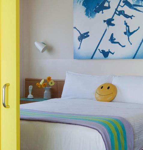 a bedroom with a bed with a smiley face pillow on it at The Beverly Laurel Hotel at West Hollywood in Los Angeles