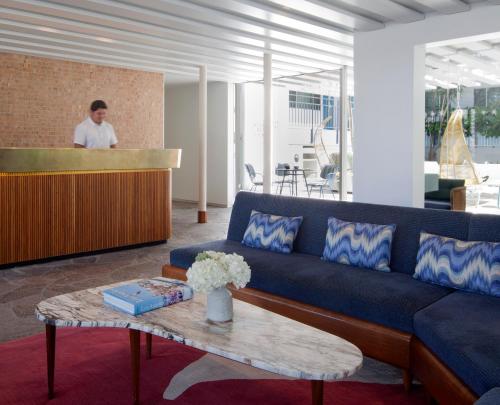 a living room with a blue couch and a table at The Beverly Laurel Hotel at West Hollywood in Los Angeles
