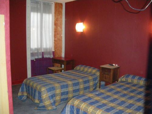 a hotel room with two beds and red walls at Hotel Restaurant du Lion d'Or in Château-Chinon