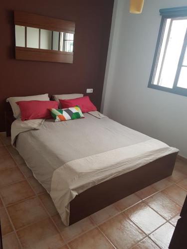 a bed in a bedroom with red and green pillows at Casa Garita Beach in Arrieta