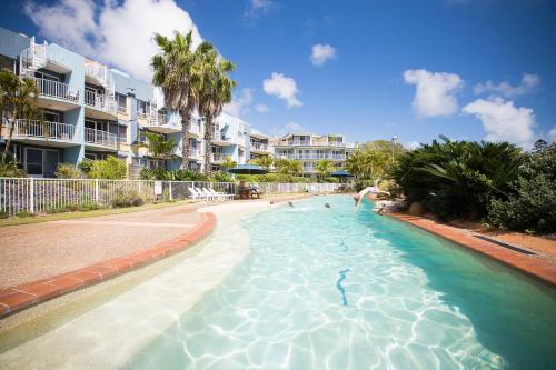 a swimming pool in a resort with people in it at BreakFree Great Sandy Straits in Hervey Bay