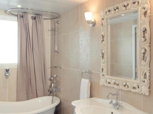 une salle de bain avec un lavabo, une baignoire et un miroir dans l'établissement Hôtel Mercure Villeneuve sur Lot Moulin de Madame, à Villeneuve-sur-Lot