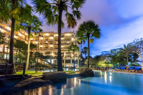 a hotel with palm trees in front of a building at Garden Sea View Resort in North Pattaya