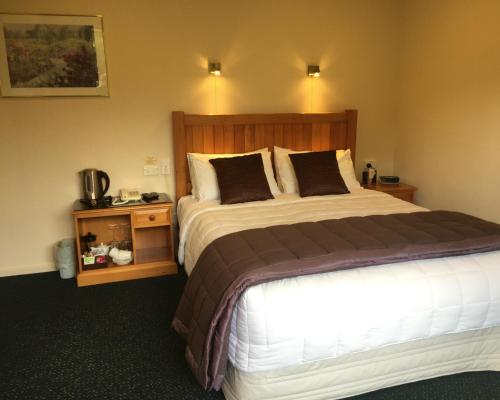 a bedroom with a large bed and a night stand at Lake Roxburgh Lodge in Roxburgh