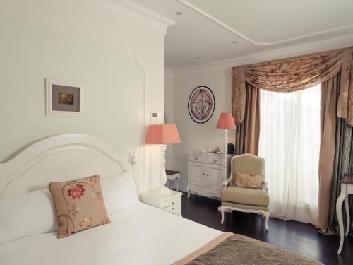 a white bedroom with a bed and a chair at Hôtel Mercure Villeneuve sur Lot Moulin de Madame in Villeneuve-sur-Lot