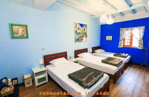 北竿鄉的住宿－家適咖啡.民宿2館 ，一间卧室设有两张床和蓝色的墙壁