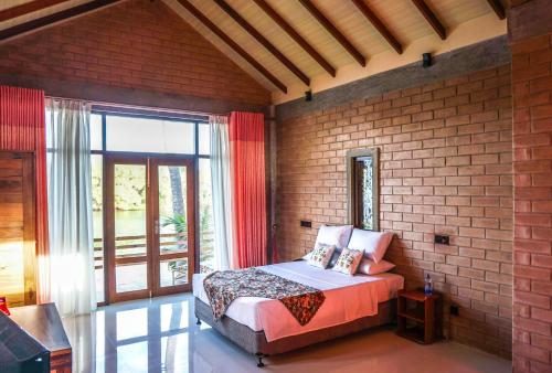 1 dormitorio con cama y pared de ladrillo en Twin Waters Resort, en Chilaw