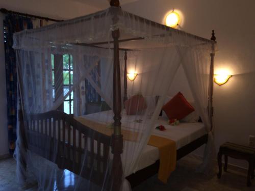 a bedroom with a canopy bed with white curtains at White Bridge House & Resort in Aluthgama