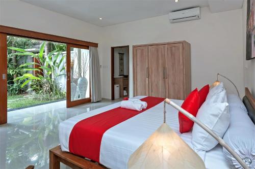 a bedroom with a large bed with red and white pillows at Rumah Indah Villa in Seminyak