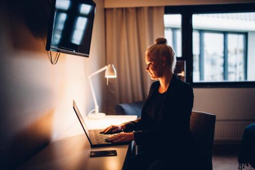 a woman sitting at a desk with a laptop at Hotel Kittilä in Kittilä