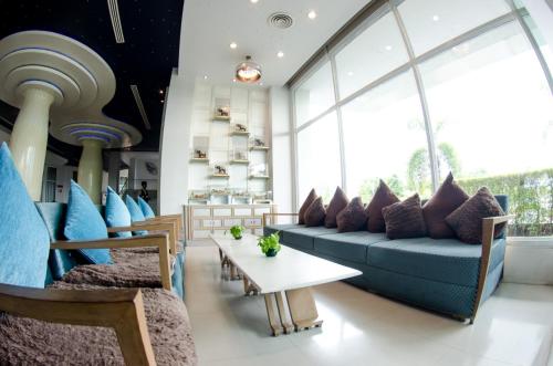 a living room with a blue couch and a table at Prajaktra Design Hotel in Udon Thani