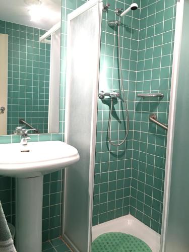 a green tiled bathroom with a shower and a sink at Apartamentos Arcos Calabardina in Calabardina