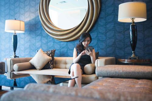 a woman sitting on a couch looking at her cell phone at Holiday Inn Express Jakarta International Expo by IHG in Jakarta